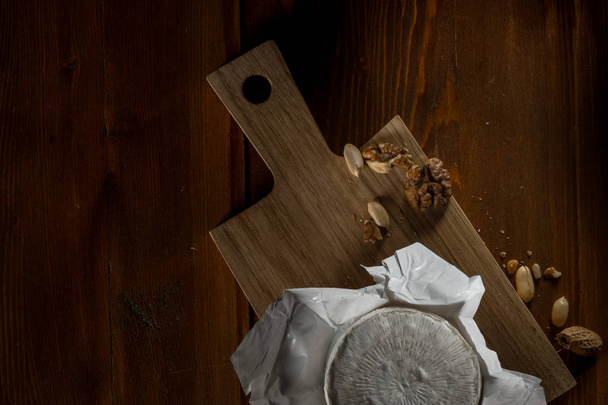 rustic flat lay with brie cheese on cutting board with nuts, top view with copy space - Φωτογραφία, εικόνα