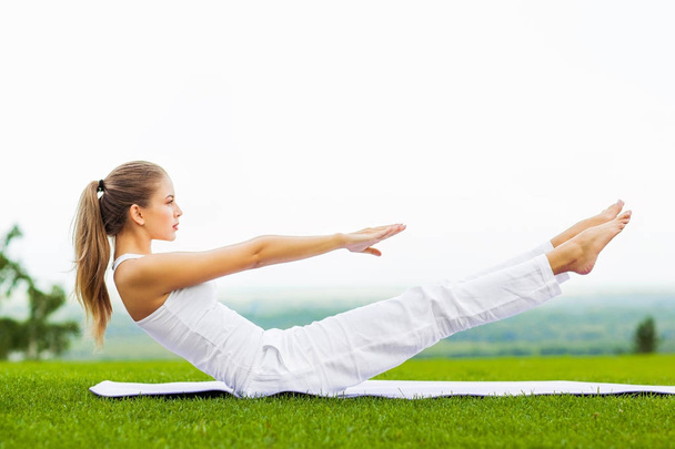 portrait of young slim woman exercising on yoga mat outdoor, healthy lifestyle, yoga and sport concept  - Photo, image