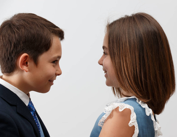 10-летняя пара братьев и сестер с радостью позирует и смотрит друг на друга, делая жесты в фотостудии на белом фоне
. - Фото, изображение
