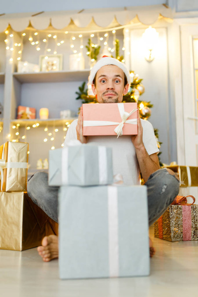Image of men in Santa caps with gift in box and pajamas - Фото, зображення
