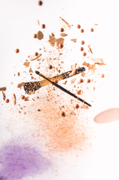 crushed cosmetic powder with makeup brushes falling isolated on white - Photo, Image