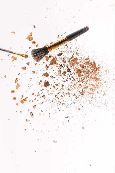 pieces of powder with makeup brushes falling isolated on white - Photo, Image