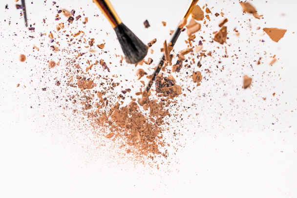 pieces of cosmetic powder with brushes falling isolated on white - Photo, image