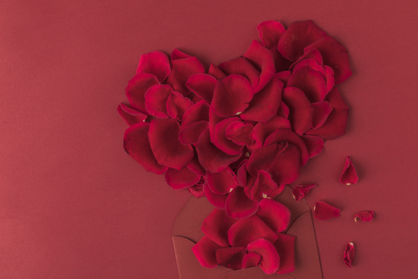 pohled shora srdce z okvětních lístků růže a obálky izolovaných na červenou, st valentines day koncept - Fotografie, Obrázek