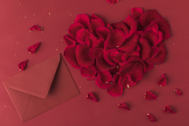 top view of heart made of roses petals and envelope isolated on red, st valentines day concept - Fotografie, Obrázek