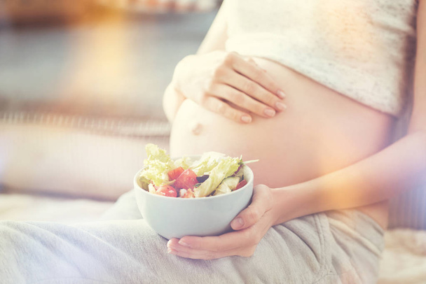 Pleasant pregnant woman holding greek salad - Fotó, kép