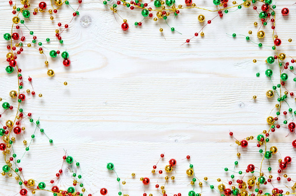 Marco de una guirnalda de colores navideños sobre una superficie de madera blanca
. - Foto, imagen