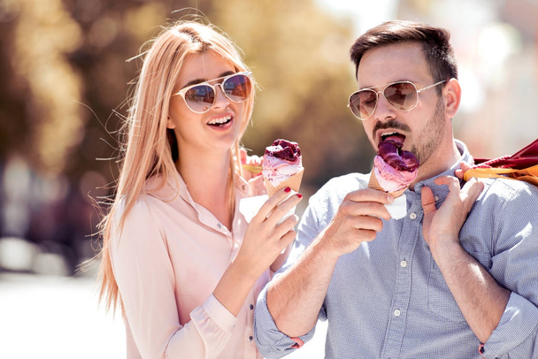 Χαρούμενο ζευγάρι τρώει παγωτό. Εικόνα από ένα υπέροχο ζευγάρι τρώει παγωτό στην πόλη. - Φωτογραφία, εικόνα