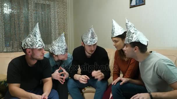 Friends in foil on the head of the house. Gathering of friends about listening to their ideas of extraterrestrial civilizations - Footage, Video
