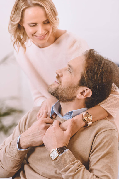 smiling wife hugging husband on wheelchair from back in bedroom - Fotografie, Obrázek
