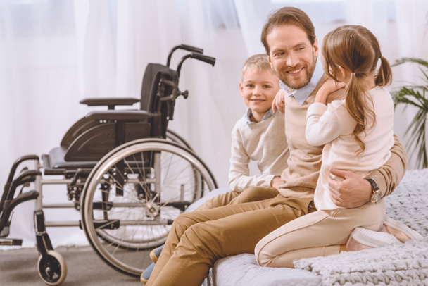 happy father with disability sitting with children on bed - Fotoğraf, Görsel