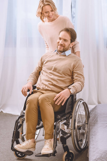 wife looking at smiling husband on wheelchair - Photo, Image