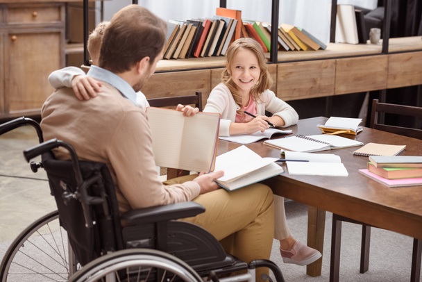 otec na invalidní vozík, učí se děti doma a objímání a syn - Fotografie, Obrázek