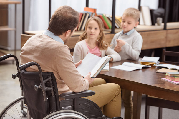 father on wheelchair teaching children at home  - Photo, Image