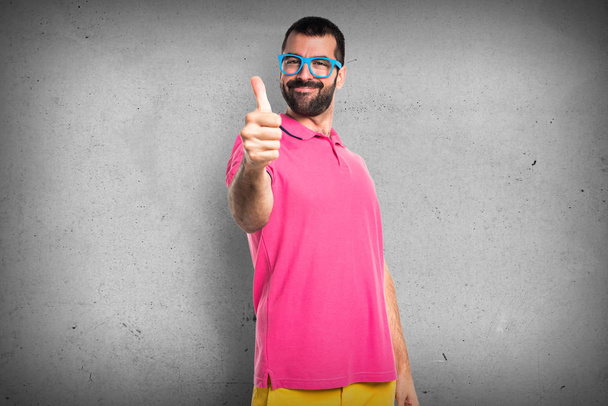 Homem em roupas coloridas com polegar para cima
 - Foto, Imagem