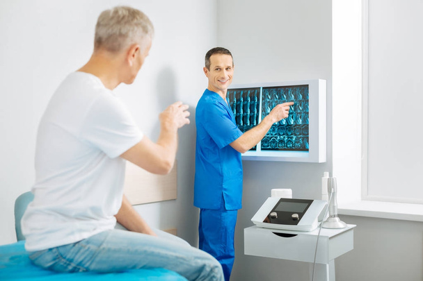 Wesoły lekarz zachwycony stojący w pobliżu X ray obrazów - Zdjęcie, obraz
