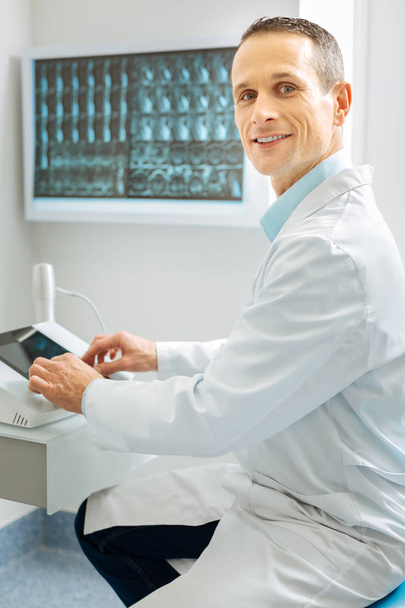 Professional male radiologist sitting near the X ray control panel - Foto, afbeelding