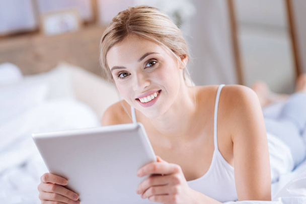 Pleasant woman smiling while using tablet - Фото, изображение