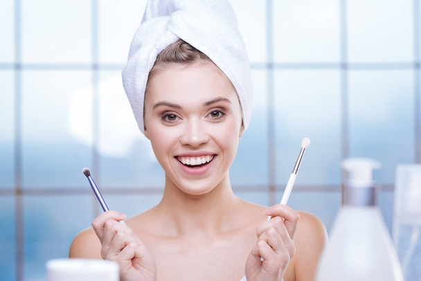 Happy young woman posing with two makeup brushes - Фото, изображение