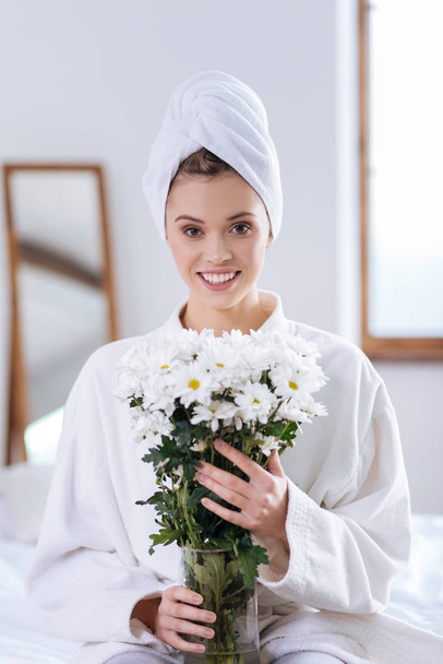 Piękna kobieta w szlafrok, trzymając wazon z kwiatami - Zdjęcie, obraz