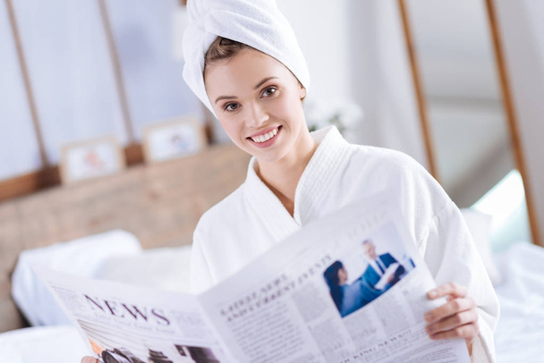 Cheerful woman reading newspaper after shower - Zdjęcie, obraz