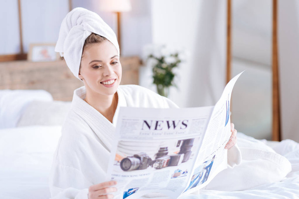 Pleasant woman in bathrobe reading news - Фото, изображение
