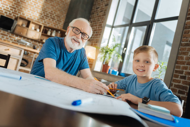 Cheerful grandfather and grandson working on a drawing - Fotó, kép