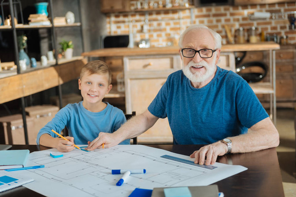 Positive smart grandfather and grandson doing a blueprint - Photo, image