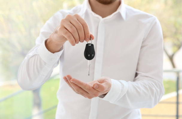 Man in formal clothes holding car key on blurred background - Foto, Bild