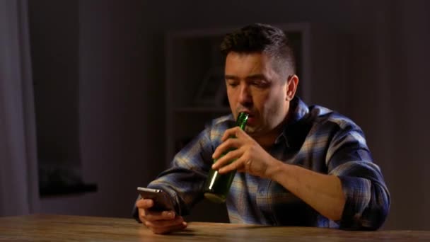 hombre con teléfono inteligente beber cerveza embotellada en casa
 - Imágenes, Vídeo