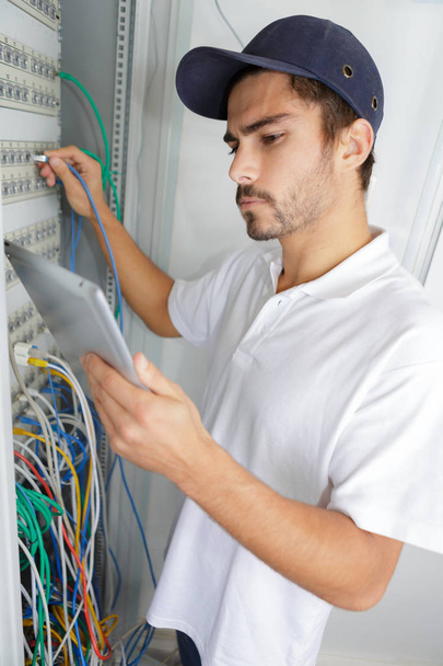 focused electrician applying safety procedure while working on electrical panel - Foto, Bild
