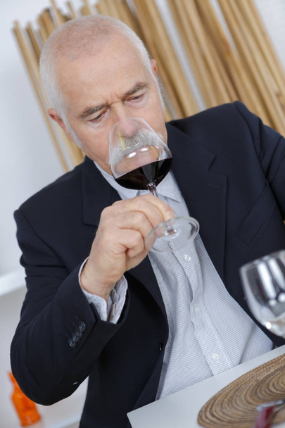 older man smelling red wine - Фото, зображення