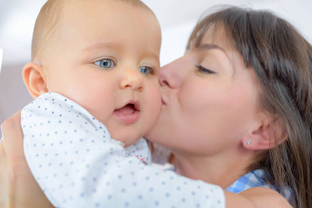 closeup of mother kissing baby - Foto, afbeelding