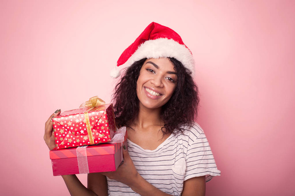 Donna afroamericana in cappello di Babbo Natale che celebra il Natale con scatole regalo
 - Foto, immagini