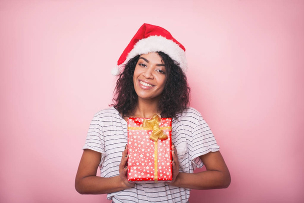 African american woman in santa hat celebrating christmas with gift boxes - Foto, Imagen