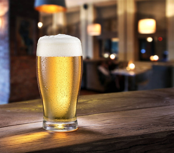 Frosty glass of light beer on the bar counter. - Φωτογραφία, εικόνα