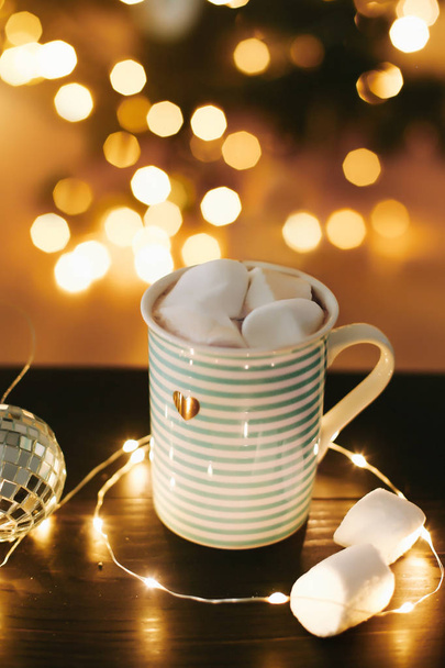 Christmas coffee cup with marshmallows on the background of New Year's lights and decorations. - Valokuva, kuva