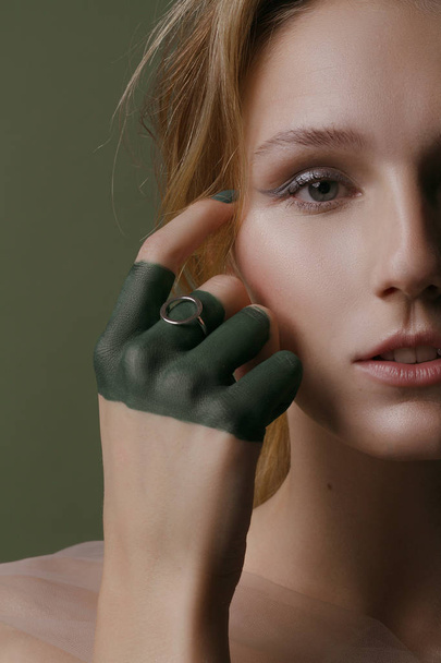Kaunis tyttö luova meikki ja hopeanhohtoinen koruja vihreällä taustalla
 - Valokuva, kuva