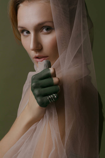 Beautiful girl with creative make-up and silvery jewelry on a green background - Foto, Bild