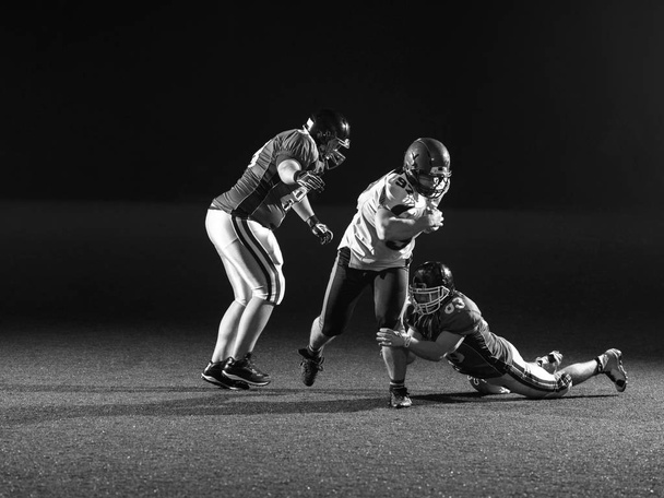 American football players in action at night game time on the field - Zdjęcie, obraz