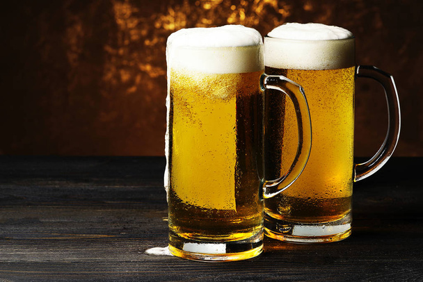 Two mugs of beer on a dark background. - Фото, изображение