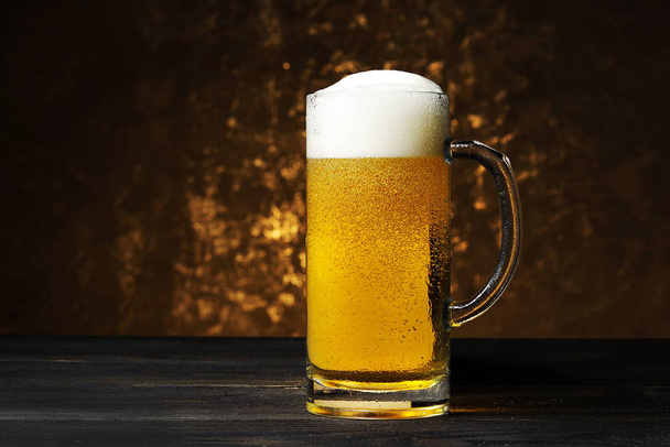 暗い背景にビールのジョッキ。暗い背景に金色のビールとガラス マグカップ. - 写真・画像