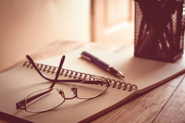 Óculos, caderno e caneta sobre mesa de madeira
. - Foto, Imagem