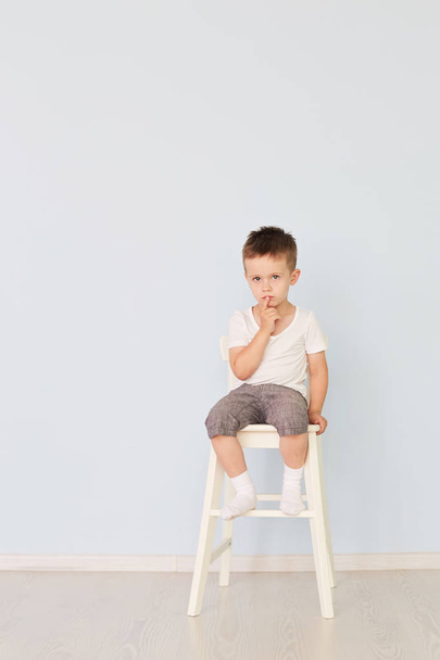 bright room. Boy in white shirt sitting in a high chair - Foto, afbeelding