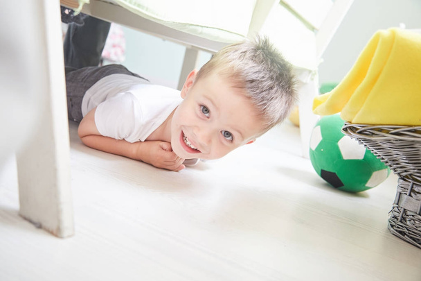 Little smiling boy is lying on a floor at home. - Фото, зображення