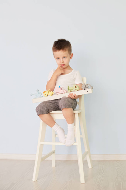a boy plays with a machine and sits on the chair - Zdjęcie, obraz