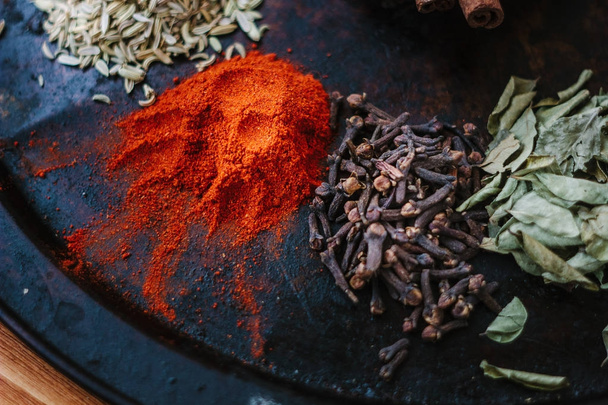 Set of spices - chili powder, cloves, curry leaves and caraway over black surface. - Fotoğraf, Görsel
