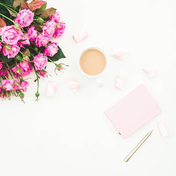 Female desk with pink roses bouquet, pink diary, coffee mug and marshmallows on white background. Flat lay. Top view feminine background. Fashion blog. - Foto, afbeelding