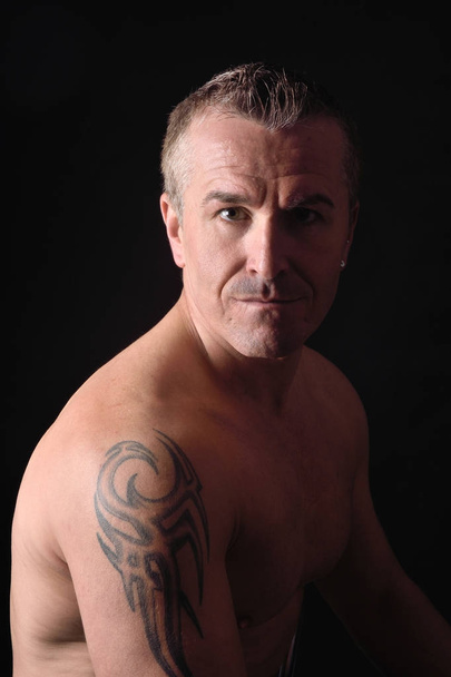 Πορτραίτο ενός άνδρα με τατουάζ και μαύρο φόντο - Φωτογραφία, εικόνα