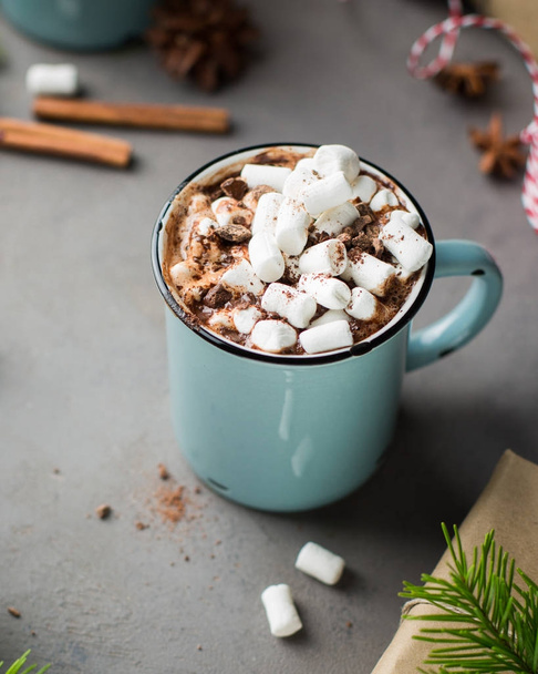 Mug of hot chocolate with marshmallow and cinnamon on a gray concrete background with a Christmas tree, gifts. and red-white string (twine). Winter xmas holidays concept. Festive mood. - Foto, imagen